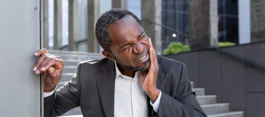 Older man holding his mouth and jaw in pain, having a dental emergency and in need of rapid treatment.