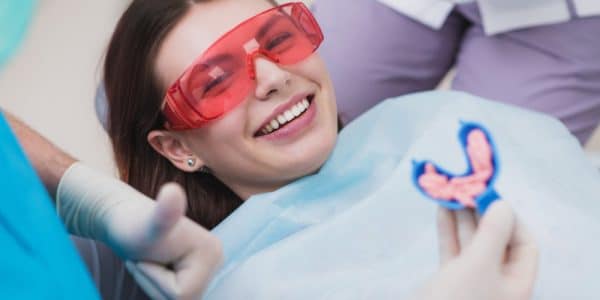 Smiling young woman receiving a fluoride treatment to prevent cavities and protect her teeth.