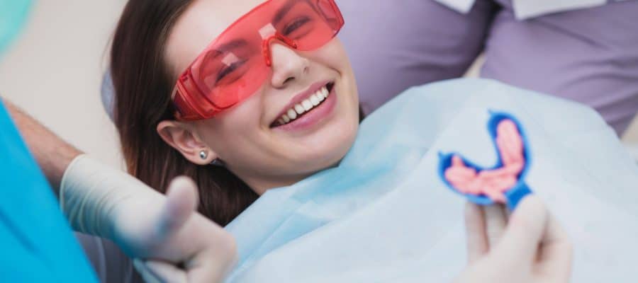 Smiling young woman receiving a fluoride treatment to prevent cavities and protect her teeth.